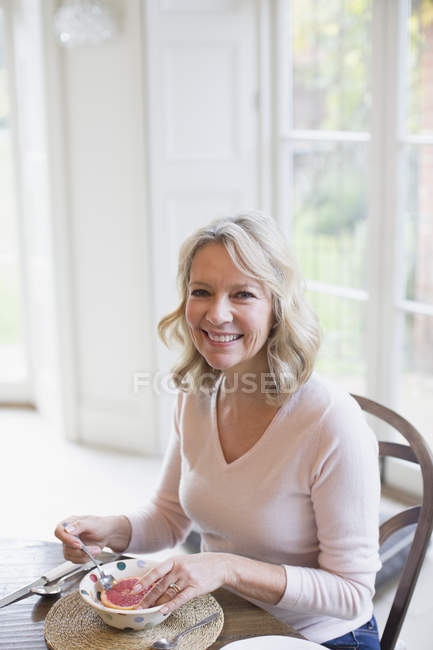 Portrait smiling mature woman eating grapefruit — Stock Photo