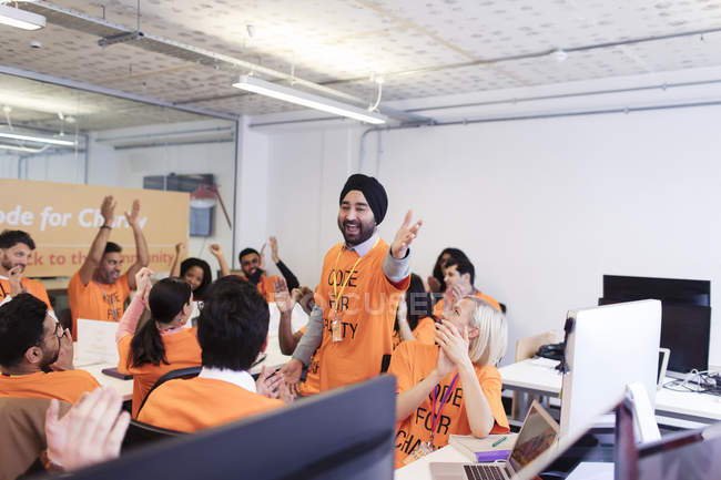 Enthusiastic hackers cheering, coding for charity at hackathon — Stock Photo