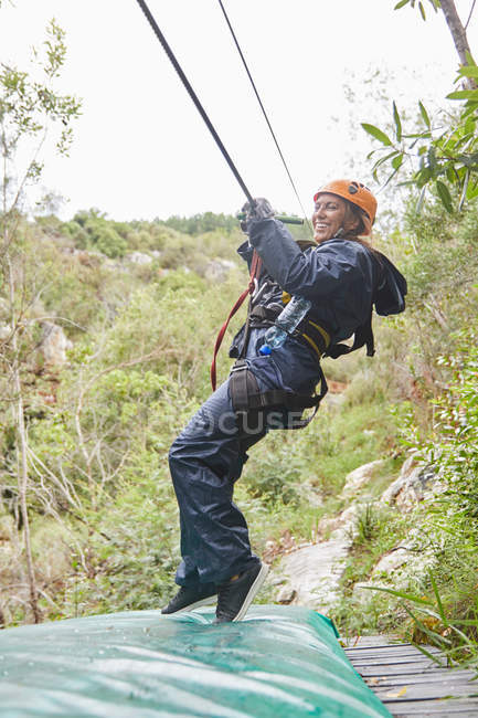 Happy woman zip lining in woods — Stock Photo