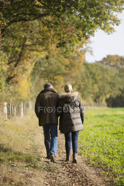 Rear view of mature caucasian couple walking together in autumn park — Stock Photo