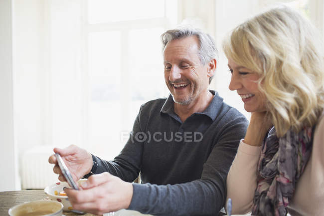 Sourire couple d'âge mûr en utilisant un téléphone intelligent — Photo de stock