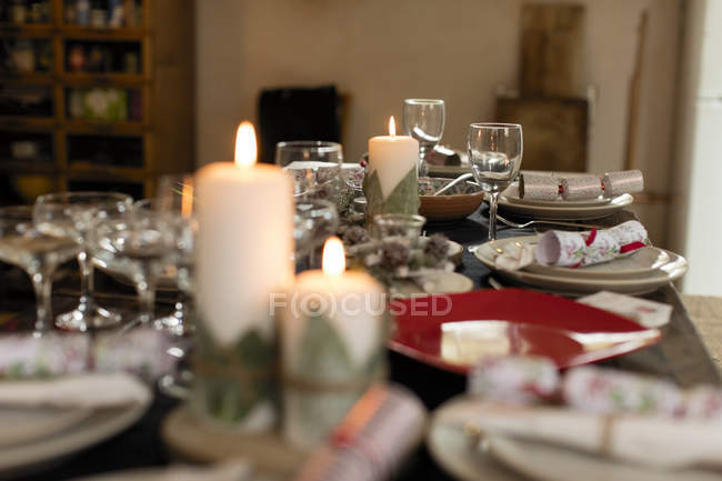 Candele, placesettings e cracker natalizi sul tavolo — Foto stock