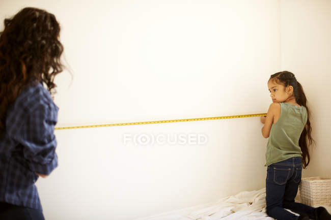 Mother and daughter measuring wall for project — Stock Photo