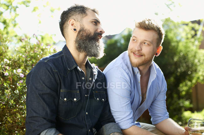Мужская гей-пара разговаривает в саду — стоковое фото
