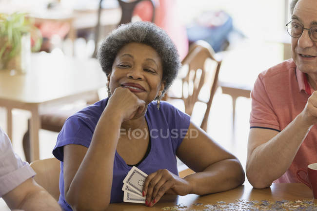 Впевнена, щаслива старша жінка грає в карти з друзями в громадському центрі — стокове фото
