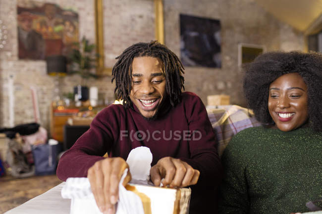 Young man opening Christmas gift — Stock Photo