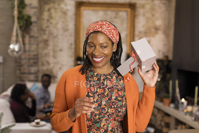 Sonriente, mujer curiosa sacudiendo regalo de Navidad - foto de stock