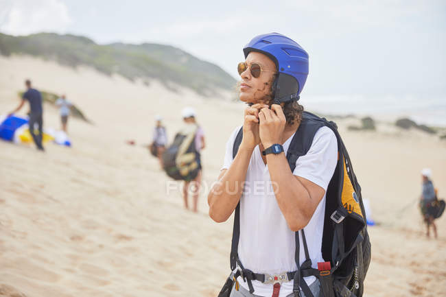 Male paraglider fastening helmet on beach — Stock Photo
