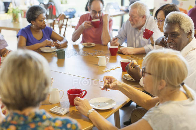 Friends drinking tea and playing games at table in community center — Stock Photo