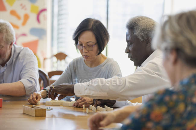 Senior friends playing mahjong at table in community center — Stock Photo