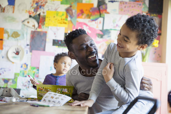 Padre afroamericano jugando con niños en casa - foto de stock