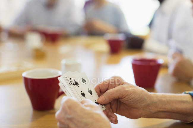 Close up senior woman playing cards with friends in community center — Stock Photo