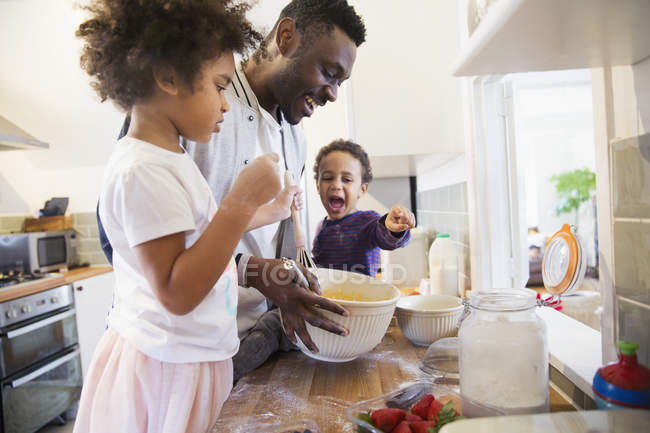 Отец и счастливые дети пекут на кухне — стоковое фото