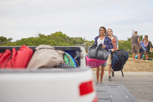 Paragliders carrying parachute backpacks to truck — Stock Photo
