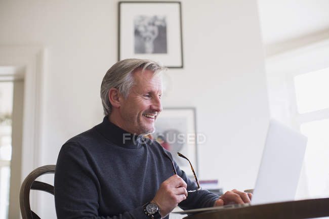 Smiling mature male freelancer working at laptop at home — Stock Photo