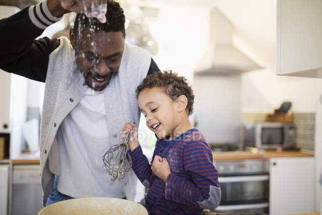 Père afro-américain préparant la nourriture avec son fils — Photo de stock