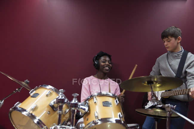 Подростковые музыканты записывают музыку, играют на барабанах и гитаре в звуковом зале — стоковое фото
