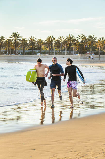 Захоплені чоловіки-серфери, що працюють з дошками для серфінгу на океанічному пляжі — стокове фото