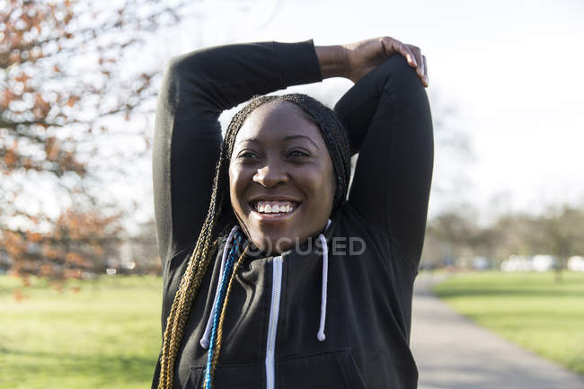 Портрет уверенной женщины бегущей с протянутыми руками в парке — стоковое фото