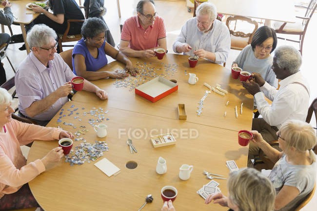 Senior friends playing games at table in community center — Stock Photo