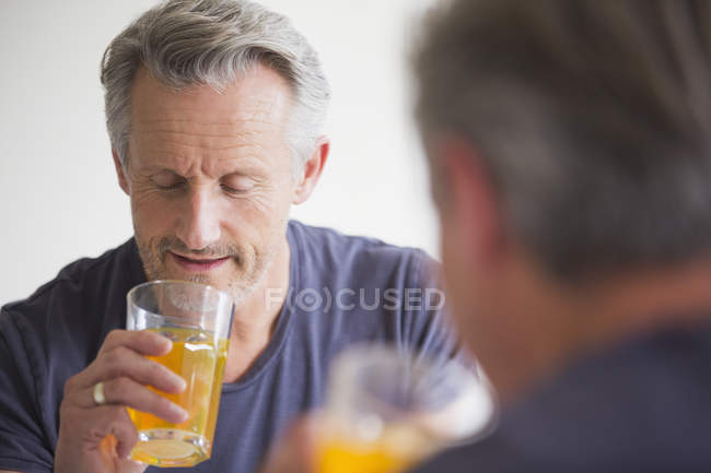 Uomo maturo che beve succo allo specchio a casa moderna — Foto stock