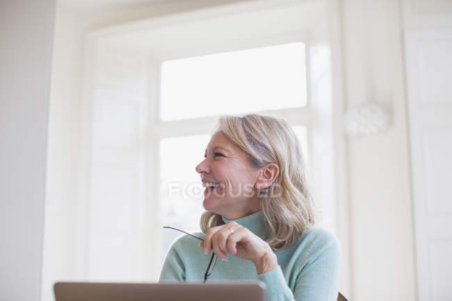 Glückliche reife Freiberuflerin, die zu Hause am Laptop arbeitet — Stockfoto