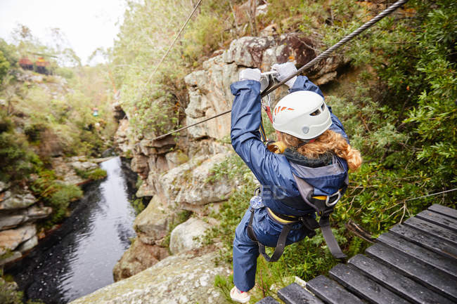 Woman zip lining over pond in woods — Stock Photo