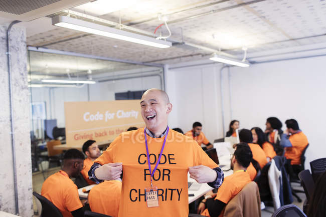 Playful hacker with t-shirt coding for charity at hackathon — Stock Photo