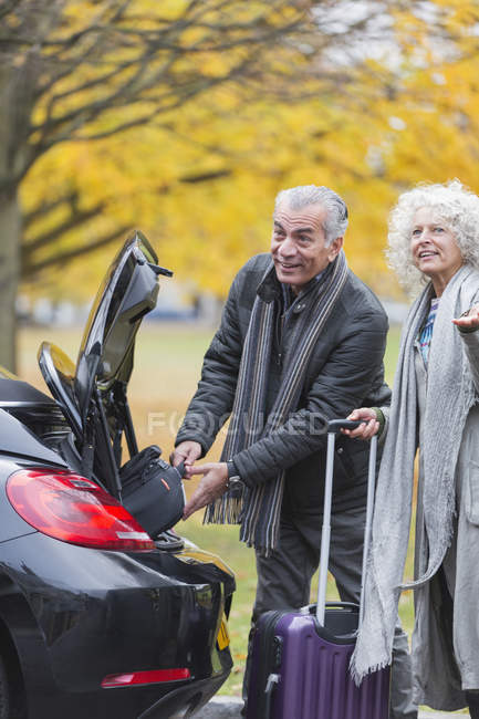Couple aîné retirer les bagages du coffre de la voiture — Photo de stock