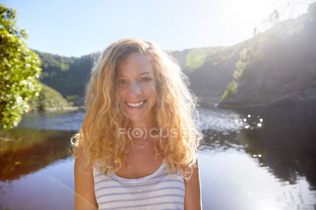 Porträt lächelnde, selbstbewusste junge Frau am sonnigen Sommersee — Stockfoto