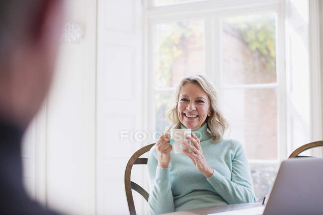 Smiling mature woman drinking tea, talking to man — Stock Photo