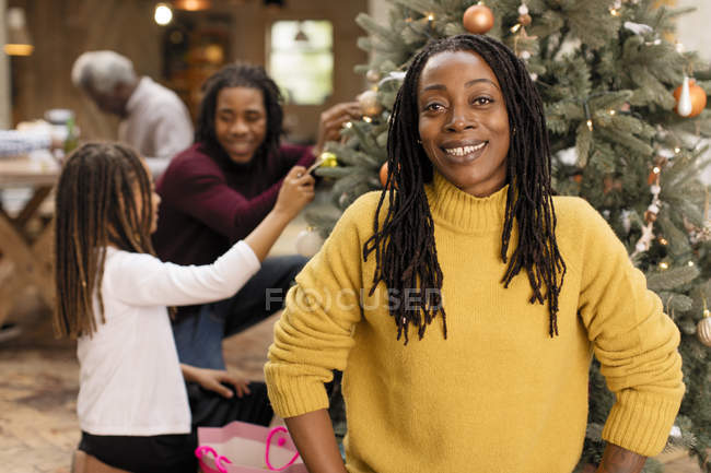 Retrato mujer sonriente decorando árbol de Navidad con la familia - foto de stock