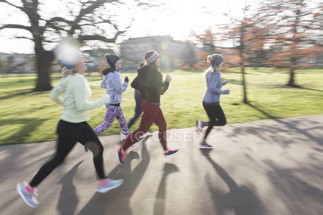 Corredores femininos correndo no parque ensolarado — Fotografia de Stock