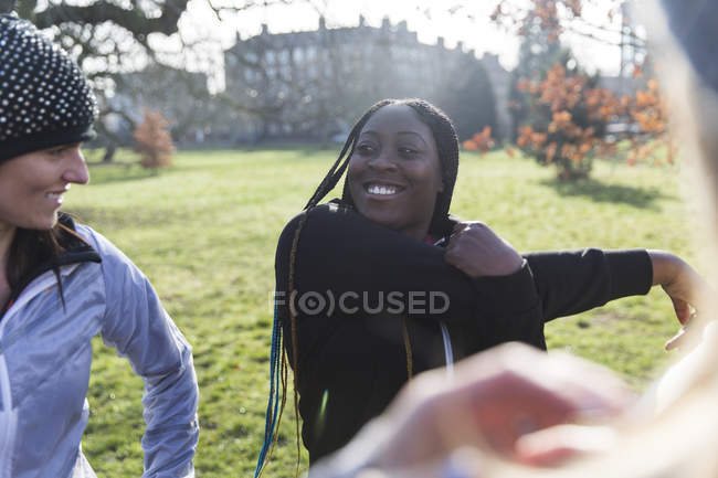 Sorridente corridore femminile che si estende nel parco soleggiato — Foto stock