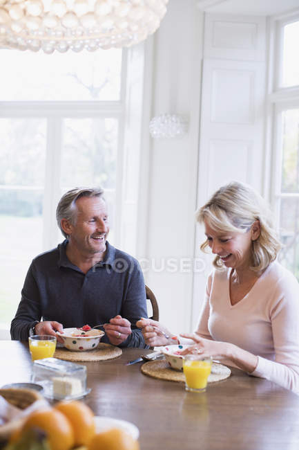 Sorrindo casal maduro tomando café da manhã na mesa de jantar — Fotografia de Stock