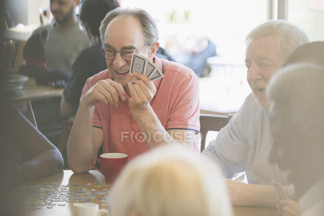 Щасливі старші друзі грають в ігри за столом у громадському центрі — стокове фото