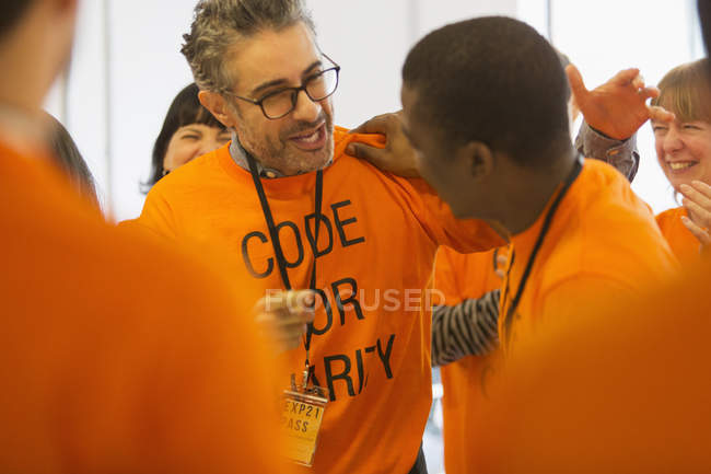 Happy hackers hugging, coding for charity at hackathon — Stock Photo