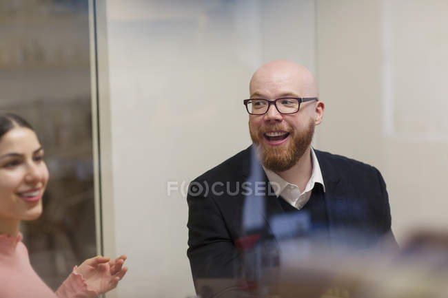 Усміхнений бізнесмен слухає колегу в офісі — стокове фото
