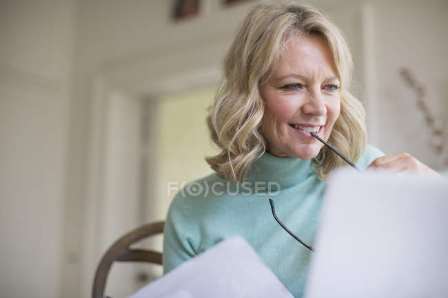 Улыбающаяся взрослая женщина-фрилансер, работающая дома за ноутбуком — стоковое фото