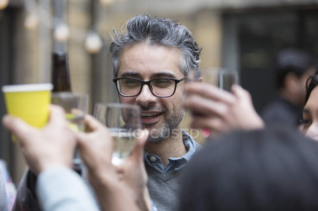 Homem feliz brindar bebidas com amigos na festa — Fotografia de Stock