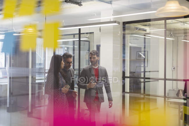Empresários caminhando e conversando no corredor do escritório — Fotografia de Stock
