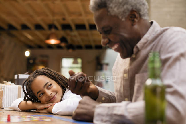 Nieta sonriente y abuelo jugando juego de mesa - foto de stock
