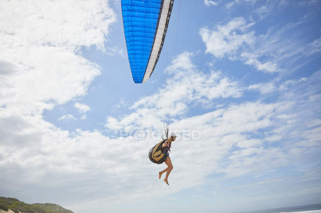 Female paraglider paragliding against sunny blue sky — Stock Photo