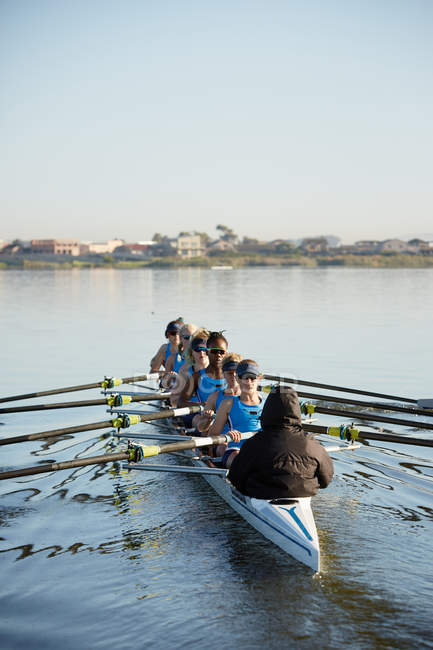 Female rowers rowing scull on sunny lake — Stock Photo