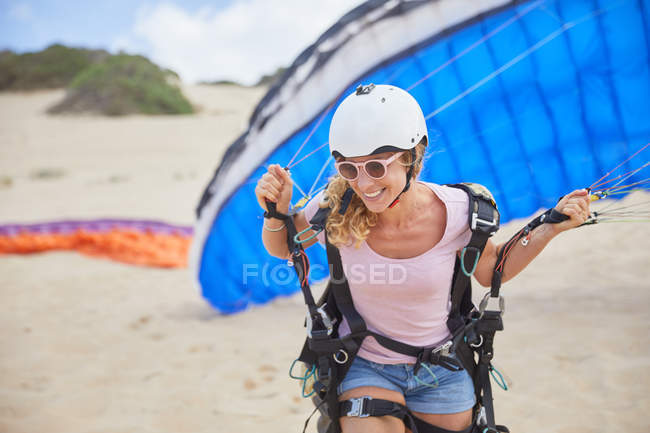 Parapendio femminile sorridente con paracadute sulla spiaggia — Foto stock