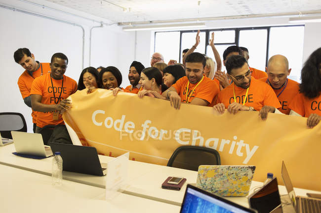 Hackers con banner codificando para caridad en hackathon - foto de stock