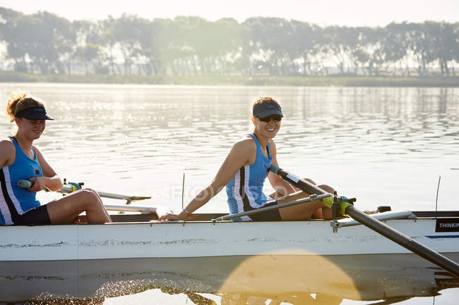 Portrait smiling female rower in scull on sunny lake — Stock Photo
