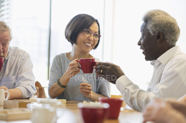 Happy senior friends enjoying tea in community center — Stock Photo