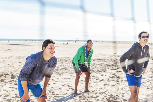 Hombres jugando voleibol de playa en la playa soleada - foto de stock