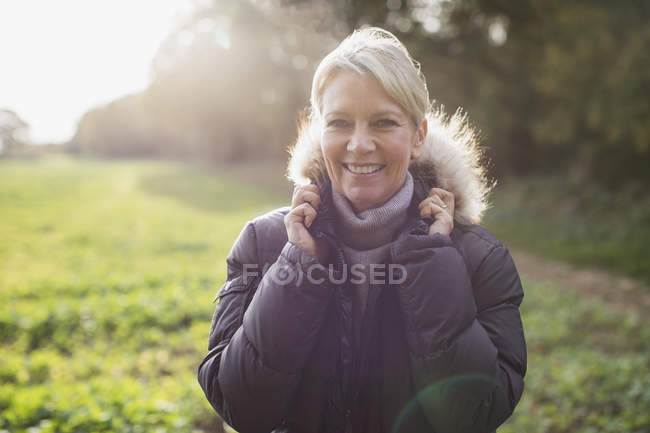 Portrait of happy blond woman in autumn outfit posing at park — Stock Photo